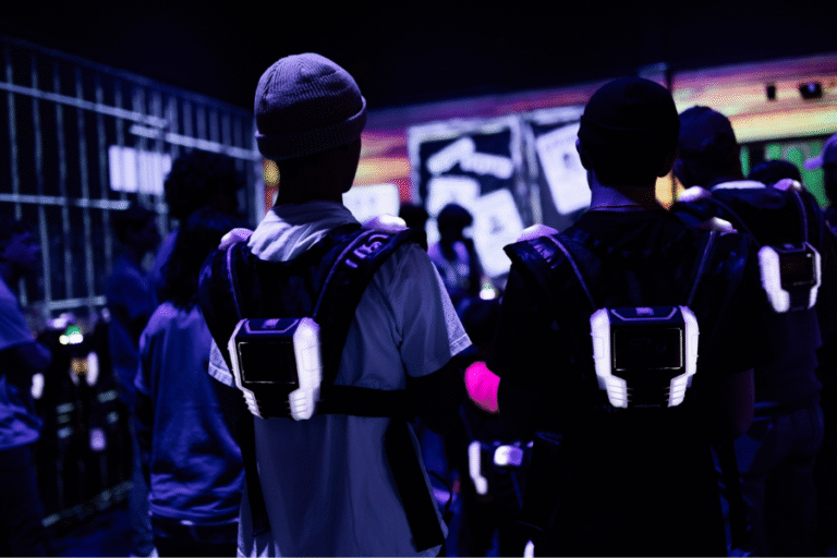 A group of people stands in front of a screen at The Rush Funplex, engaged and looking towards the display.