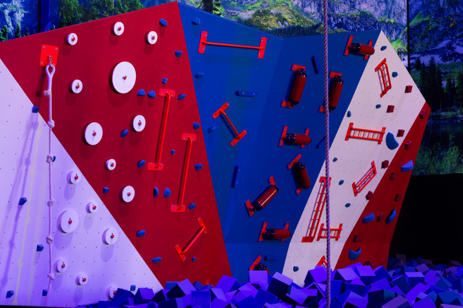 Climbing wall at The Rush Funplex featuring vibrant red, white, and blue colors.