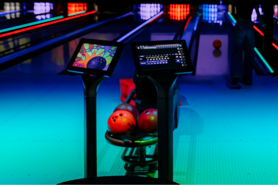 A bowling alley at The Rush Funplex featuring a screen and a colorful bowling ball on the lane.