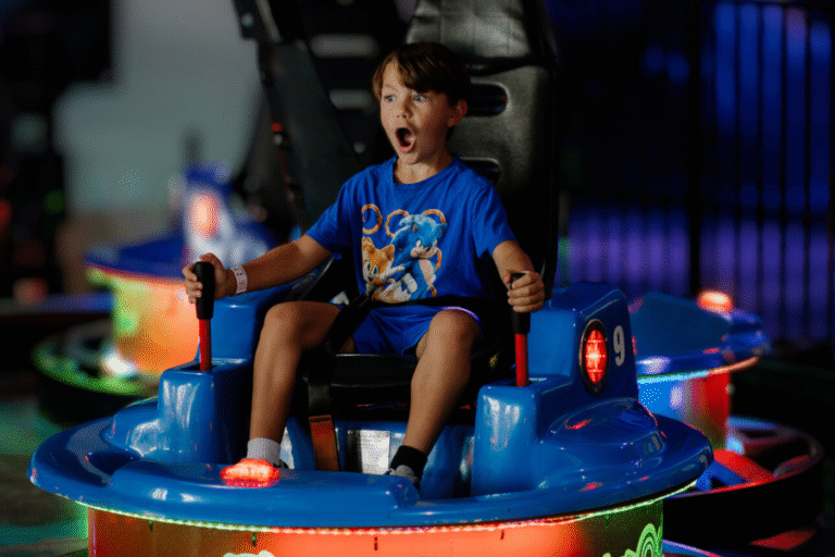 A young boy enjoys riding a bumper car at The Rush Funplex amusement park, smiling as he navigates the colorful attraction.
