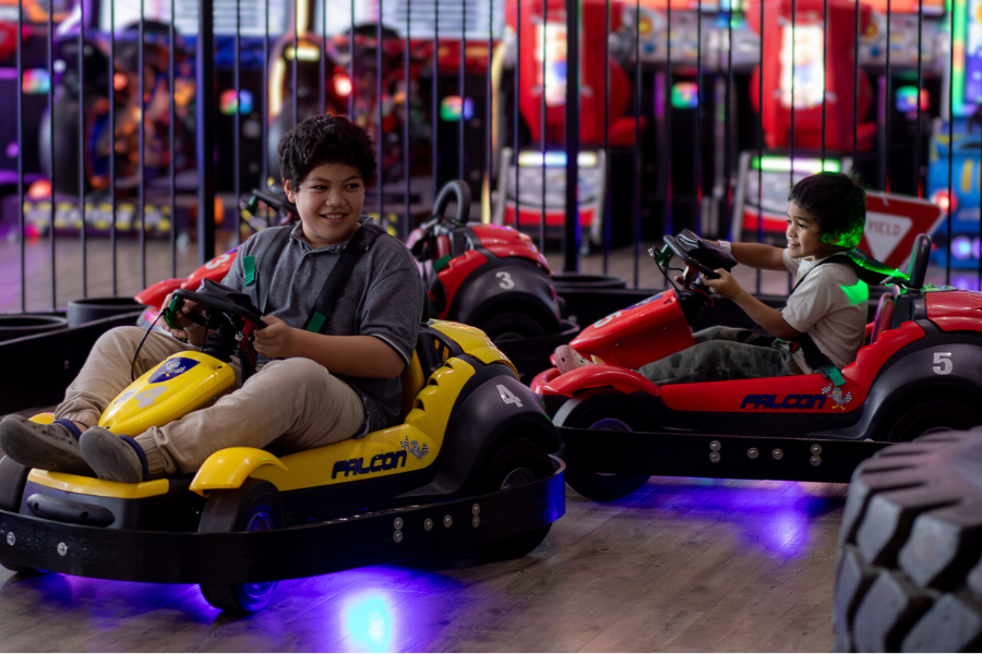 A group of people stands in front of a screen at The Rush Funplex, engaged and looking towards the display.