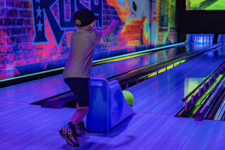The Rush Funplex bowling alley, illuminated by colorful lights, with a large screen showcasing scores and entertainment.