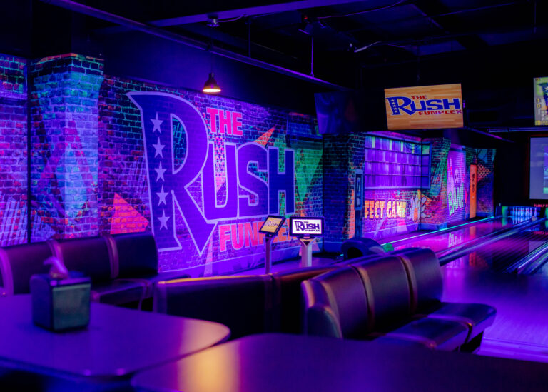 Interior view of Rush Funplex bowling alley in San Diego, featuring lanes, bowling balls, and players enjoying the game.