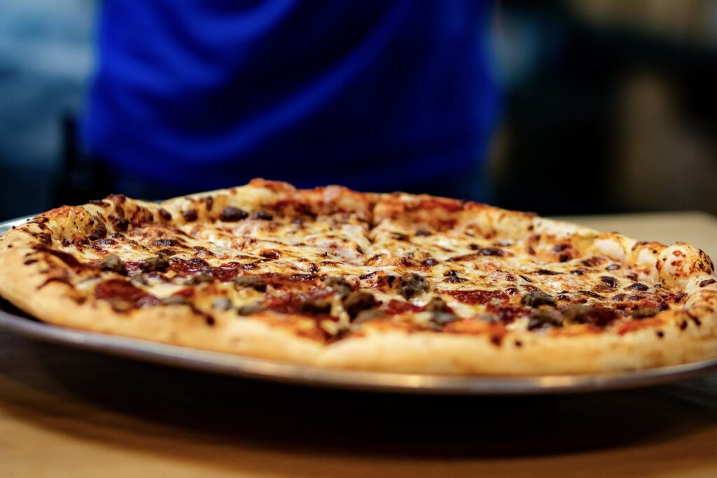 A delicious pizza displayed on a metal pan, ready to be enjoyed at The Rush Funplex.